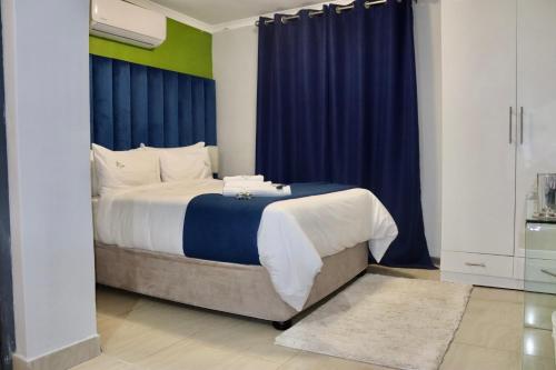 圣约翰港Uzuri Lifestyle的一间卧室配有一张带蓝色窗帘的大床