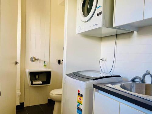 拜伦湾Poolside Apartment In Central Byron的一个带水槽和洗衣机的小厨房