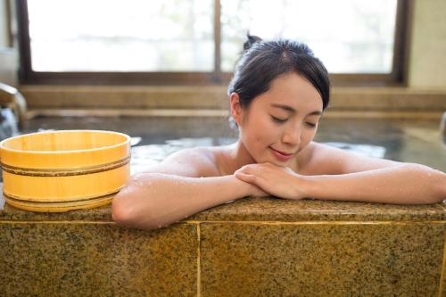 伊势市Yawarano-yu MARUYA For women only的躺在浴缸里的一个妇女,浴缸里有一个黄色的碗