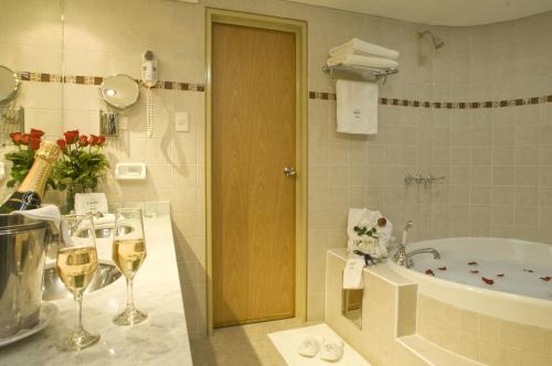 内乌肯Land Express Neuquén的浴室配有浴缸和淋浴,提供葡萄酒