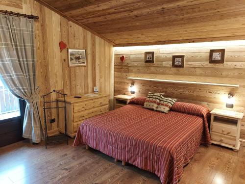 艾马维尔Hotel Rendez-Vous - Aymavilles的木制客房内的一间卧室,配有一张床