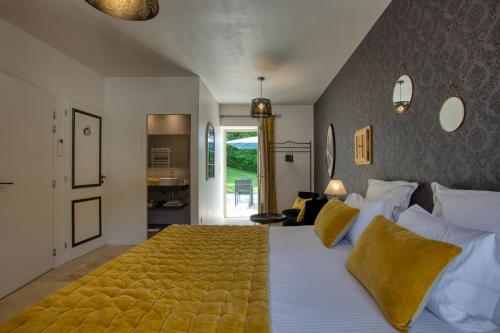 CarluxDomaine des Pierres Blanches - Chambres d'Hôtes的一间卧室配有一张带白色床单和黄色枕头的大床。