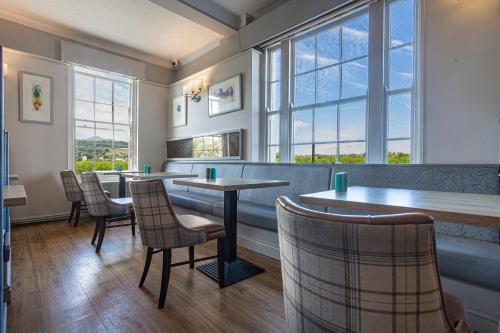 布雷肯The Castle Of Brecon Hotel, Brecon, Powys的餐厅设有桌椅和窗户。