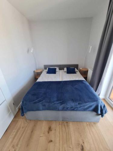 姆热日诺Apartament CARO的一间卧室配有一张带蓝色毯子的床