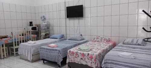 库亚巴Aluguel de loft mobiliado em Cuiabá的一间设有三张床的客房,墙上设有一台电视。