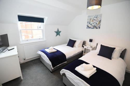 埃克斯茅斯Strand House Flat 2 Free Parking, by RentMyHouse的一间卧室设有两张床、一张桌子和一个窗口。