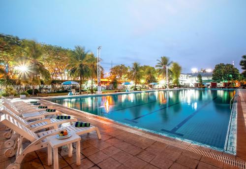 泗水Surabaya Suites Hotel Powered by Archipelago的一个带椅子和棕榈树的大型游泳池