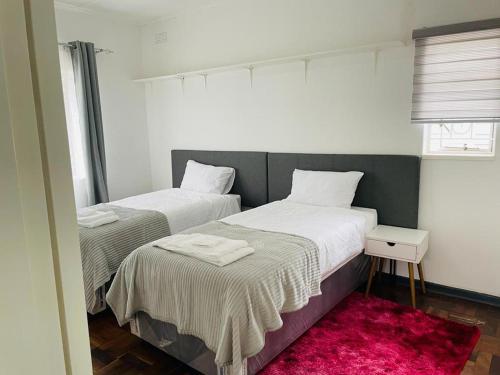 布拉瓦约Remarkable 2-Bed House in Bulawayo的红色地毯小客房内的两张床