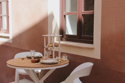 卡斯特罗·德波利亚斯Hotel Palau Macelli的一张桌子、两把白色椅子和窗户