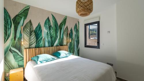皮耶特罗塞拉Les Rivages de Stagnola Appartement T3 vue mer et montagne plage 200m climatisé的一间卧室配有一张带叶子壁画的床