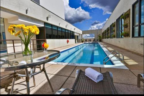 巴西利亚Flat 1015 - Comfort Hotel Taguatinga的一座带玻璃桌和椅子的游泳池位于一座建筑旁边