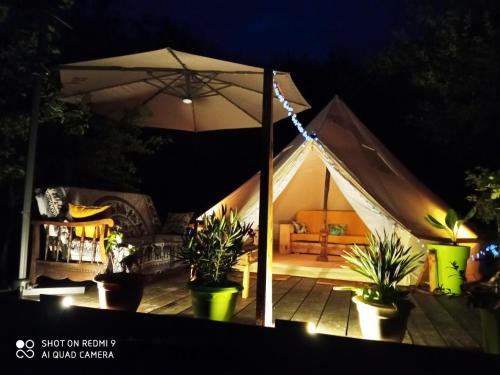 Vielle-TursanTENTE SAFARI LODGE DANS FORET LUXURIANTE的夜间带沙发和雨伞的帐篷
