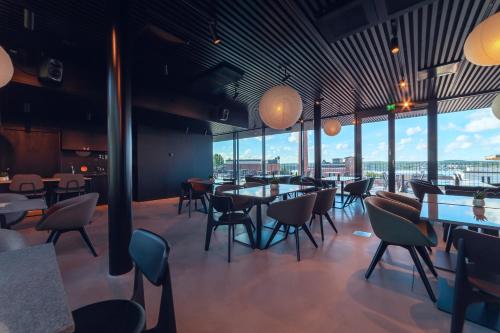 坦佩雷UNITY Tampere Trikootehdas的餐厅设有桌椅和大窗户。