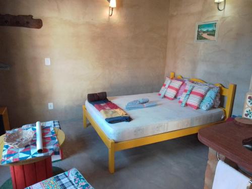 卡兰卡斯Chalé Caiçara的一间卧室配有黄色的床和色彩缤纷的枕头