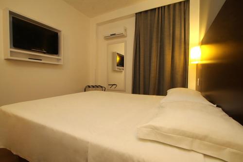 大坎普艾佩MS酒店的卧室配有白色床和平面电视