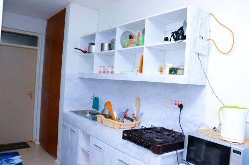 KiambuLaMeg Furnished Studio in Coral Bells Apartment的厨房配有水槽、炉灶和白色橱柜。