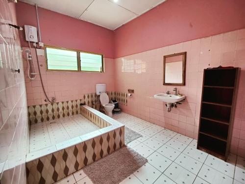 库马西Tumi Hostel的粉红色的浴室设有卫生间和水槽