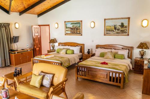 Au Cap卡瓦列罗别墅酒店的一间卧室配有两张床、一张沙发和一把椅子