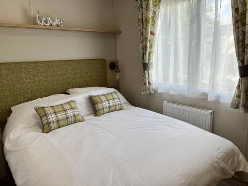 尚克林3 Bedroom Caravan MC34, Lower Hyde, Shanklin, Isle of Wight的卧室内的一张带两个枕头的白色床