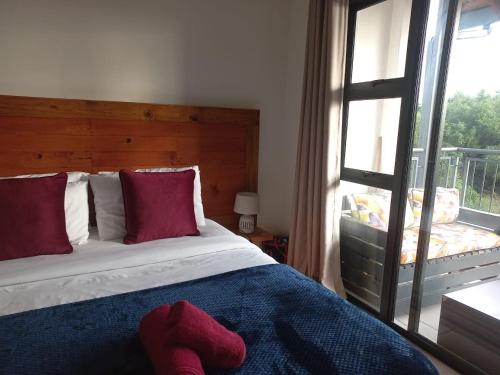 比勒陀利亚The Blyde Modern Oasis Pretoria的一间卧室配有一张带红色枕头的床和一扇窗户