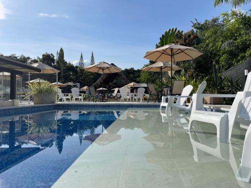 阿纳波伊马拉玛西亚精品酒店的一个带白色椅子和遮阳伞的游泳池