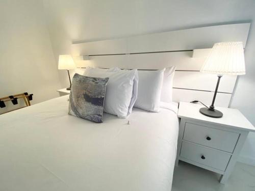 迈阿密海滩Zen Vacation Rentals Modern Penthouse Across Ocean的一张带枕头的白色床和一盏灯
