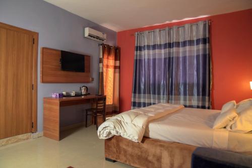 努瓦克肖特Dialali Hôtel Nouakchott的一间卧室配有一张床、一张书桌和一台电视