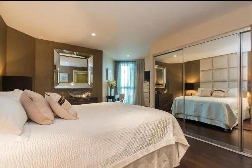 伦敦River Panorama Central London 2 bedroom New Development的卧室配有一张白色大床和镜子