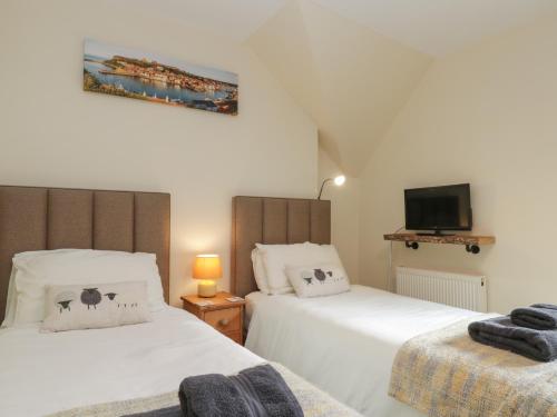 滨海索尔特本Foulsyke Farm Cottage的一间卧室设有两张床,墙上配有电视。