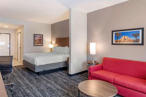 大教堂城Best Western Plus Desert View Inn & Suites的酒店客房,配有一张床和一张红色的沙发