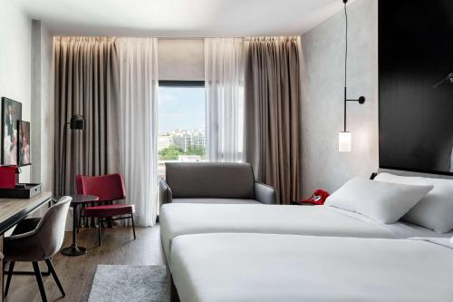 马德里Radisson RED Madrid的酒店客房配有两张床和一张书桌