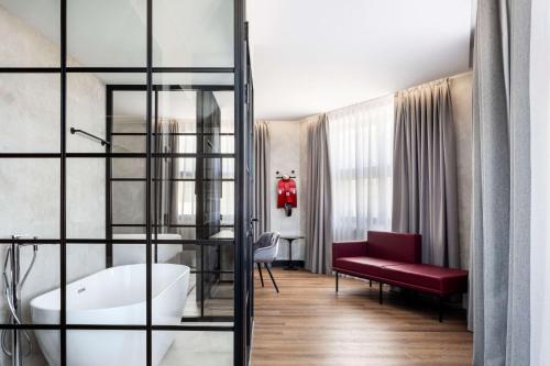 马德里Radisson RED Madrid的一间位于客房内的带红色长凳和浴缸的浴室