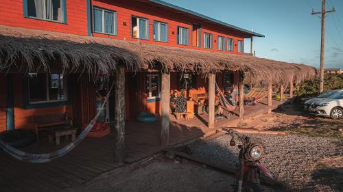 德尔迪阿布罗角Compay Hostel Punta del Diablo的一座带稻草屋顶的建筑和停在外面的一个停车场