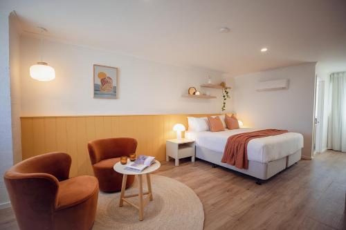 爱丽丝湾Sunnymead Hotel的一间卧室配有一张床、两把椅子和一张桌子