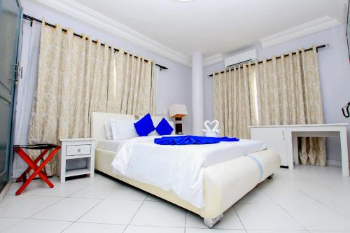 科托努Hotel Galilée的白色卧室配有一张带蓝色枕头的大床