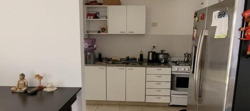 埃塞萨House near ezeiza international airport的厨房配有白色橱柜和不锈钢冰箱