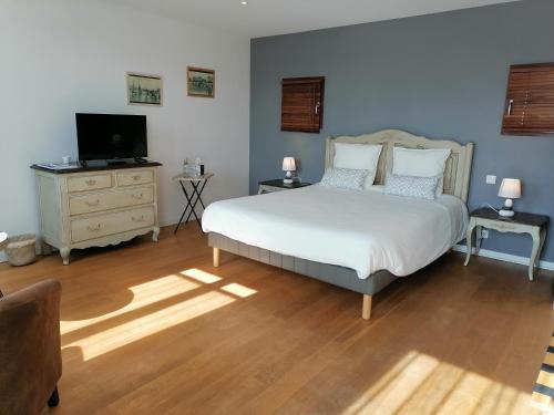 莱萨布勒-多洛讷La Longère des Olonnes的卧室配有白色的床和电视。