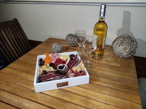 乌伊斯特勒昂Nuit insolite sur l'eau au port de Ouistreham的木桌上的一盒食物,配酒杯