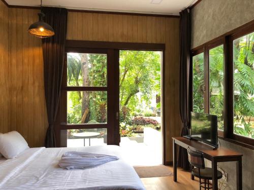 班佩Likita Resort的一间卧室配有一张床、一张书桌和一个窗户。