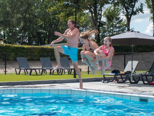 瓦赫宁根TopParken – Recreatiepark de Wielerbaan的一名男子和两名儿童跳入游泳池