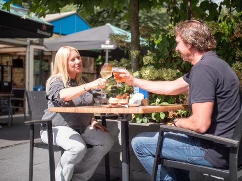 瓦赫宁根TopParken – Recreatiepark de Wielerbaan的坐在桌边饮酒的男人和女人