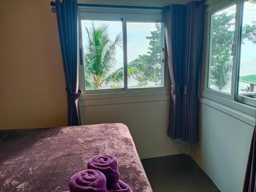象岛Cliff View Bungalows的客房设有窗户,床上配有紫色毛巾