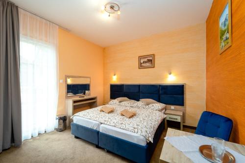 斯祖贝莱克Penzion Josu的一间卧室配有蓝色的床、一张书桌和一个窗户。