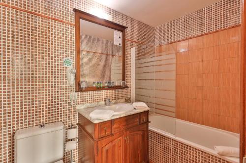 圣特罗佩海滩酒店的一间带水槽、浴缸和镜子的浴室