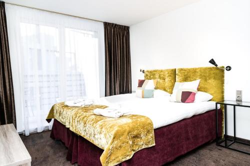 考纳斯HOF HOTEL的一间卧室配有一张大床和金色床罩