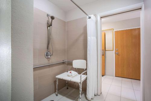 南派恩斯Microtel Inn & Suites by Wyndham Southern Pines Pinehurst的浴室内配有带白色椅子的淋浴