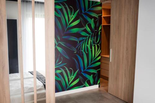 若雷Apartament Południowy W80的一间卧室,墙上挂着植物壁画