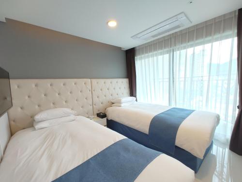 巨济Hotel STAYON的配有窗户的酒店客房内的两张床