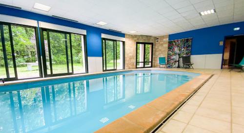 Vienne-le-Château图里皮埃尔餐厅酒店的一个带蓝色墙壁和窗户的大型游泳池