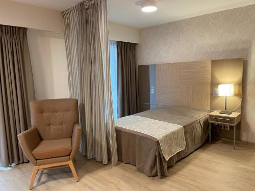 艾克斯莱班Aix-les-Bains Appart'S的一间卧室配有一张床、一把椅子和一盏灯